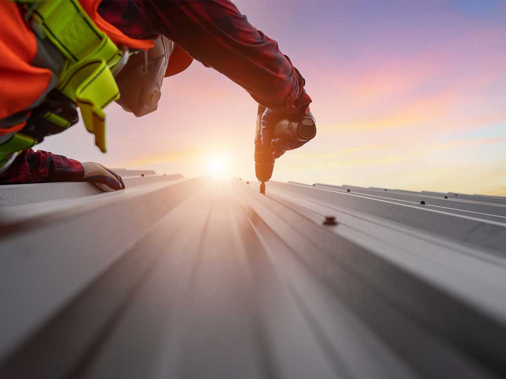 Professional roofer working on metal roof